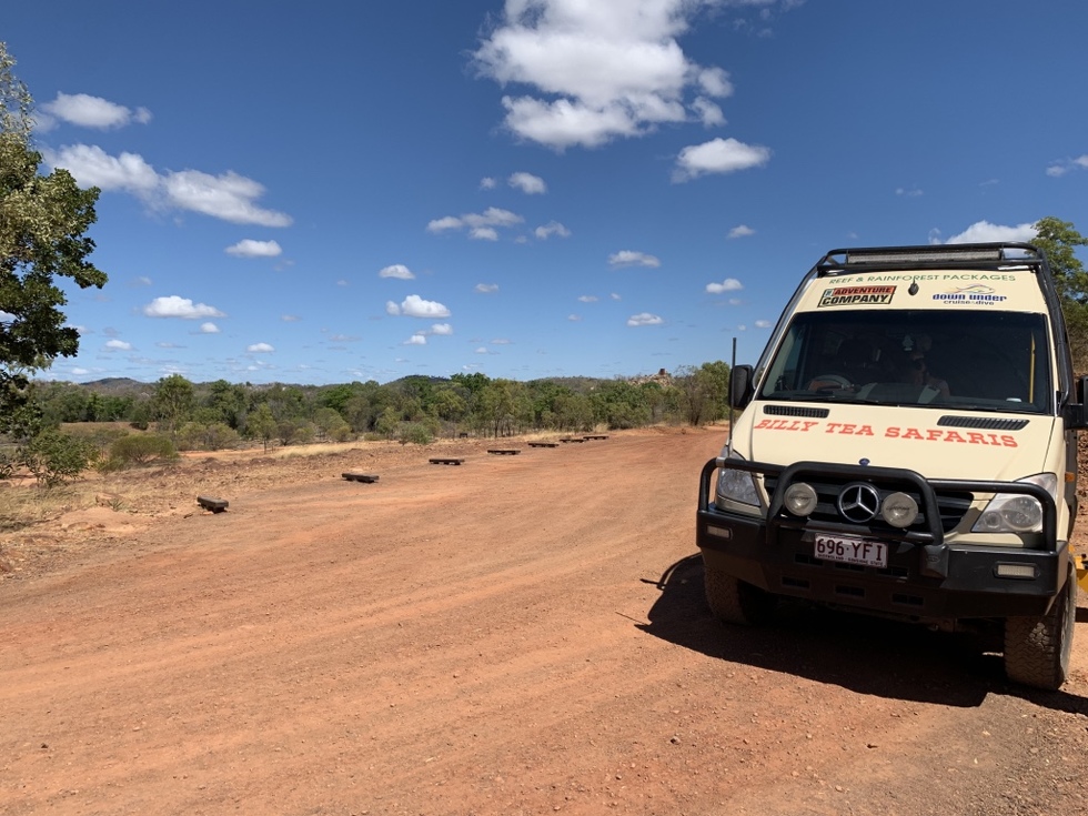クィーンズランドアウトバックの茶褐色の道をドライブ